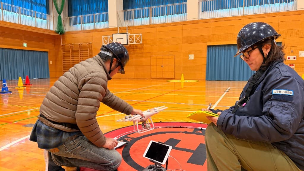 送信機とタブレットで飛行映像を確認する様子
